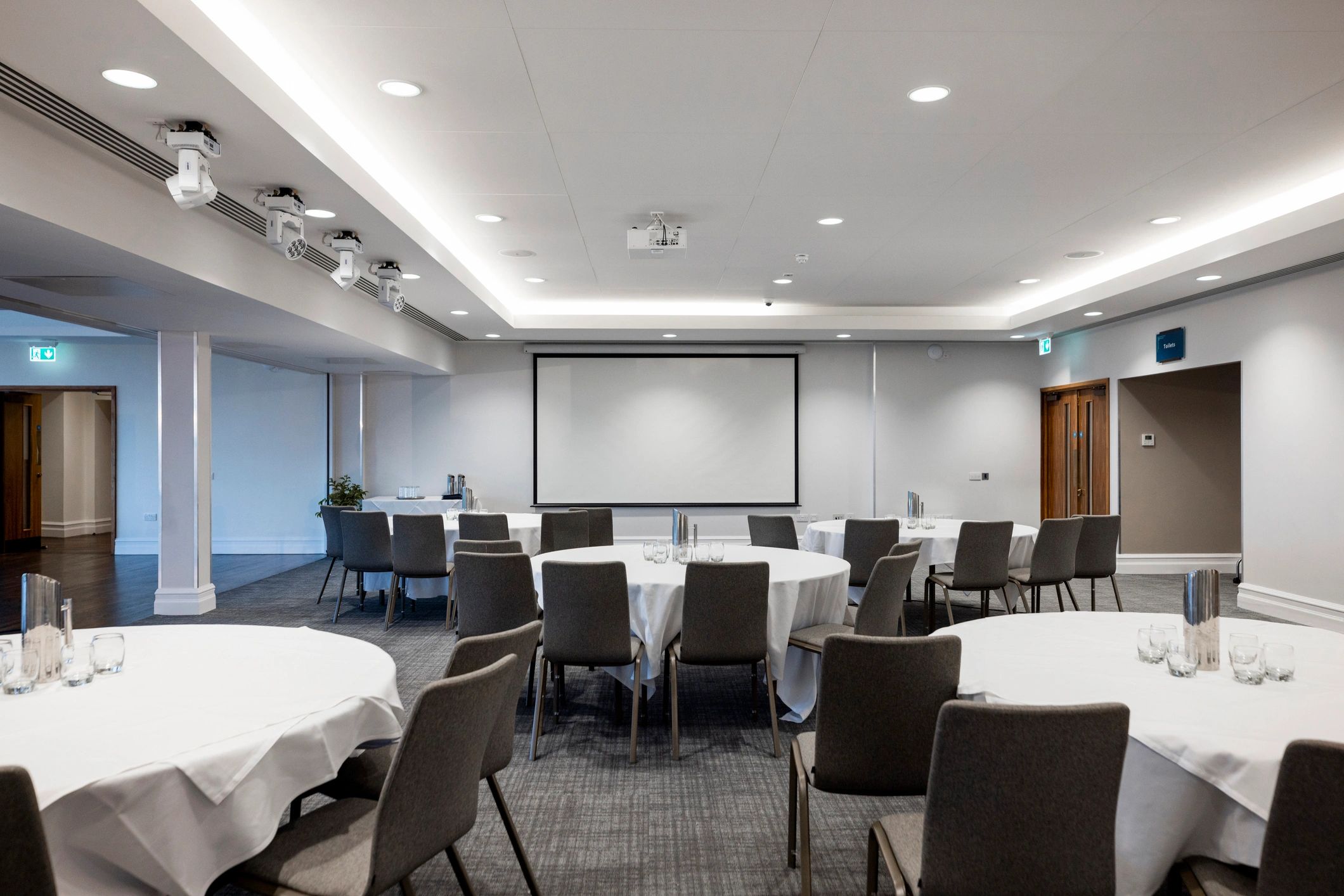 Breakout meeting room setup with tables and projector screen